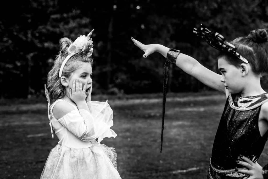 Two young girls in playful costume in a dramatic scene outdoors.